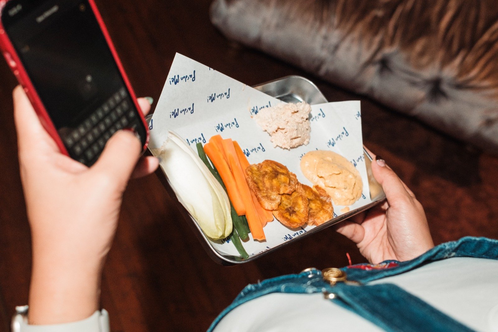 A guest holding a basket of crudité with tostones